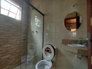 uma casa de banho com um WC, um chuveiro e um lavatório. em Chalé Canto Da Vila Ibitipoca em Conceição do Ibitipoca