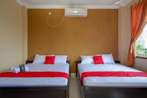 two beds with red pillows in a room at RedDoorz At Telaga Mulya Hotel Wates in Yogyakarta