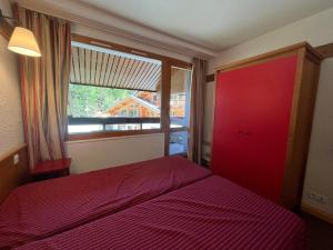 1 dormitorio con cama roja y ventana en Appartement Plagne 1800, 2 pièces, 4 personnes - FR-1-351-40, en Plagne 1800