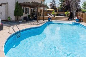 a large blue swimming pool in front of a house at Luxe Oasis Retreat: LG Grp, Pool, BBQ, 4BR, AC! in Winnipeg
