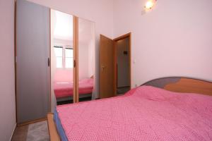 a bedroom with a pink bed and a mirror at Apartments with a parking space Pirovac, Sibenik - 6246 in Pirovac