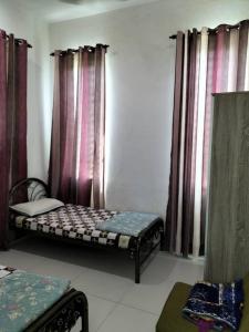 a room with two beds in a room with curtains at Noorsyah Homestay Stadium Utama in Kangar