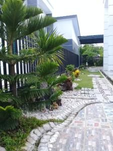 a garden with palm trees and a stone walkway at Noorsyah Homestay Stadium Utama in Kangar