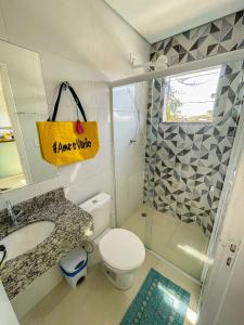 a bathroom with a toilet and a shower and a yellow sign at Mangata Loft - Requinte e Conforto para Lazer ou Trabalho in Itanhaém