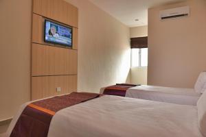 a hotel room with two beds and a tv on the wall at Geopark Hotel Kuah Langkawi in Kuah