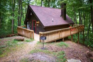 een kleine hut in het bos met een groot terras bij Wild Columbine - Gatlinburg Area Hottub Romantic Cabin in Sevierville