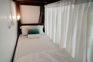 uma cama num quarto com cortinas brancas em Mystay Hostel Nan em Nan