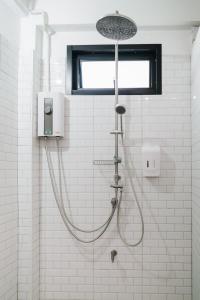 a shower in a white tiled bathroom with a shower head at Mystay Hostel Nan in Nan