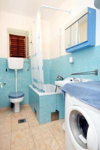 a bathroom with a toilet and a sink and a washing machine at Apartments by the sea Veli Iz, Iz - 6255 in Veli Iž