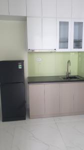 cocina con nevera negra y armarios blancos en Era Apartment Xuân Thuỷ, en Hanói