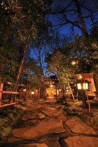 Una escena nocturna de un camino en un bosque en Kurokawa Onsen Oyado Noshiyu en Minamioguni
