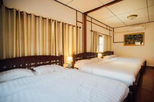 three beds in a room with white sheets at Nu Phen Homestay in Chiang Mai