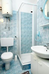 Apartments by the sea Brgulje, Molat - 6243 في مولات: حمام من البلاط الأزرق مع مرحاض ومغسلة