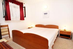 a bedroom with a large wooden bed and red curtains at Apartments by the sea Brgulje, Molat - 6243 in Molat