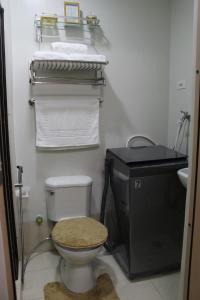 a bathroom with a toilet and a sink and towels at Whole Condo with Pool Great for Staycation in Manila