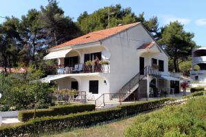 a white house with a balcony and trees at Apartments by the sea Brgulje, Molat - 6241 in Brgulje