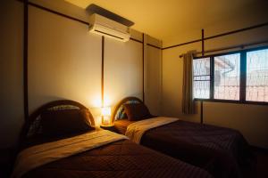 two beds in a room with a window and a lamp at Nu Phen Homestay in Chiang Mai