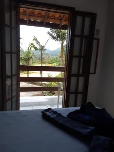 um quarto com uma cama e uma porta com vista em Chalés Carioca Prumirim Ubatuba em Ubatuba