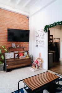 Mystay Hostel Nan في نان: غرفة معيشة مع جدار من الطوب مع تلفزيون بشاشة مسطحة