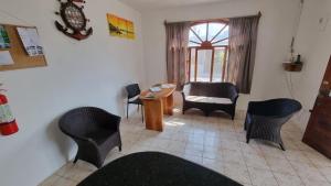 a living room with chairs and a table and a window at Hostal Poseidon - Neptuno in Puerto Villamil