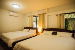 two beds in a room with a window at Nu Phen Homestay in Chiang Mai