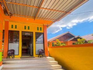Hotel Karunia 2 Jailolo في Porniti: منزل برتقالي وأصفر مع كرسيين على الشرفة