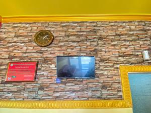 a stone wall with a tv and a clock on it at Hotel Karunia 2 Jailolo in Porniti