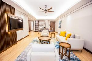 uma sala de estar com mobiliário branco e uma televisão de ecrã plano em Villea Port Dickson em Porto Dickson