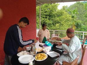 a group of people sitting around a table eating food at Riverbench Homestay Munnar, Anaviratty in Anaviratty