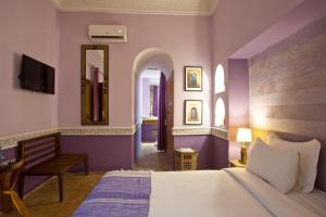 1 dormitorio con paredes moradas, 1 cama y espejo en Riad Enchanté en Marrakech