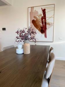 a dining room table with a vase of flowers and a painting at 3 Bedroom Apartment over looking Newcastle in Newcastle