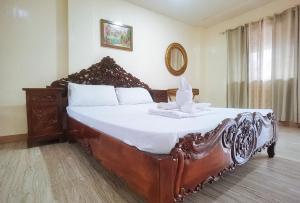 a bedroom with a large wooden bed with white sheets at RedDoorz @ Los Ecijanos Inn Pangasinan in Bolinao