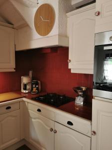 a kitchen with white cabinets and a clock on the wall at La Maison d'Yvonne in La Bouille