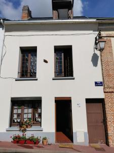 een wit gebouw met ramen en bloemen ervoor bij La Maison d'Yvonne in La Bouille