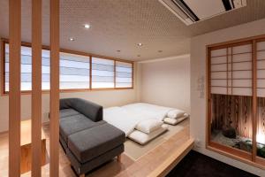 京都市にあるRinn Gion Kenninji Villa（鈴 祇園建仁寺別邸）のベッド1台、ソファ、窓が備わる小さな客室です。