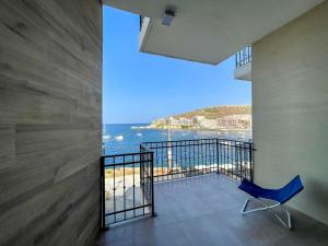 a balcony with a blue chair and a view of the ocean at Sea-view Apartment in Marsalforn in Marsalforn