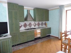 uma cozinha com armários verdes e uma televisão em Appartamento Stumiaga di Fiavè em Fiavè