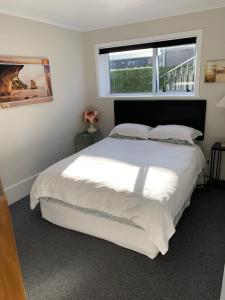1 dormitorio con 1 cama blanca grande y ventana en Beside the sea, park up and relax - Just 20 steps to the beach - Wi-Fi & Linen, en Whitianga