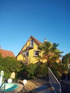 a yellow house with a palm tree and a surfboard at Zum Aufstieg in Ohlsbach
