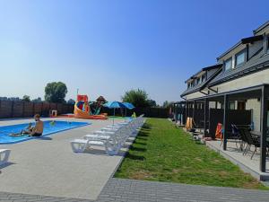 a swimming pool with lounge chairs and a playground at OSADA JANTAR in Jantar