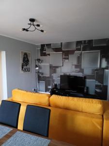 un salon avec un canapé jaune et une télévision dans l'établissement Apartament Sucharskiego, à Gdynia