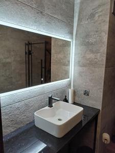 La salle de bains est pourvue d'un lavabo blanc et d'un miroir. dans l'établissement Apartament Sucharskiego, à Gdynia