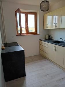 a kitchen with white cabinets and a black counter top at Apartament Sucharskiego in Gdynia