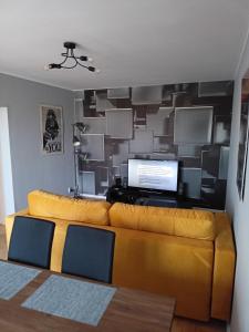 a living room with a yellow couch in front of a wall at Apartament Sucharskiego in Gdynia
