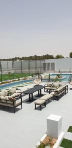 a patio with couches and a table and a pool at VENESIA chalet in Al Kāmil