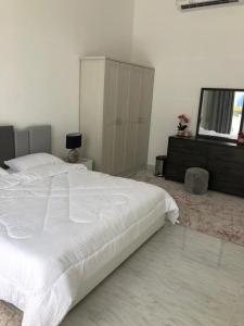 ein Schlafzimmer mit einem großen weißen Bett und einer Kommode in der Unterkunft VENESIA chalet in Al Kāmil