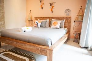 a bedroom with a large wooden bed with pillows at THE SPARE ROOM BALI in Canggu