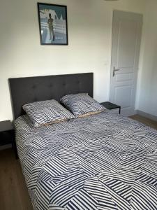 uma cama com um edredão preto e branco e 2 almofadas em l’ Aval em Étretat