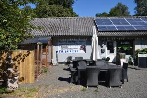 a table with an umbrella and a building with solar panels at The parrot hotel, live in a rescue animal park in Næstved
