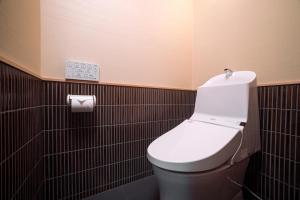 a bathroom with a white toilet in a black tiled wall at Rinn Gion Kenninji in Kyoto